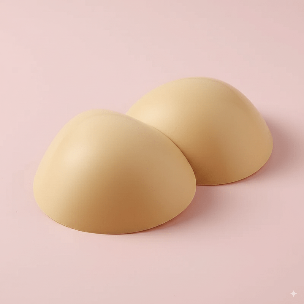 Beige silicone bra insert pads on a pink background